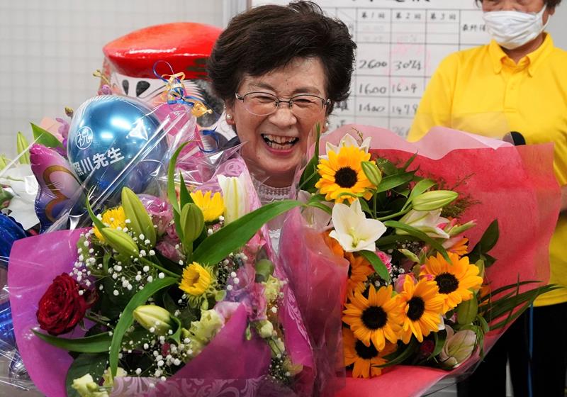 当選祝いの花束を抱えて笑顔を見せる照川氏=8月28日、勝浦市