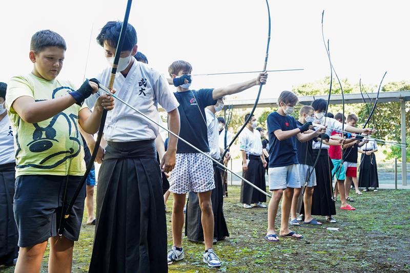 大学生に教えてもらいながら弓道を体験するウクライナやポーランドの少年たち＝３０日、勝浦市