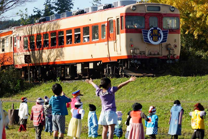 いすみ鉄道の「キハ28」が定期運行を終了。沿線にはかかしと一緒に車両に向かって手を振る子どもの姿があった=27日、いすみ市
