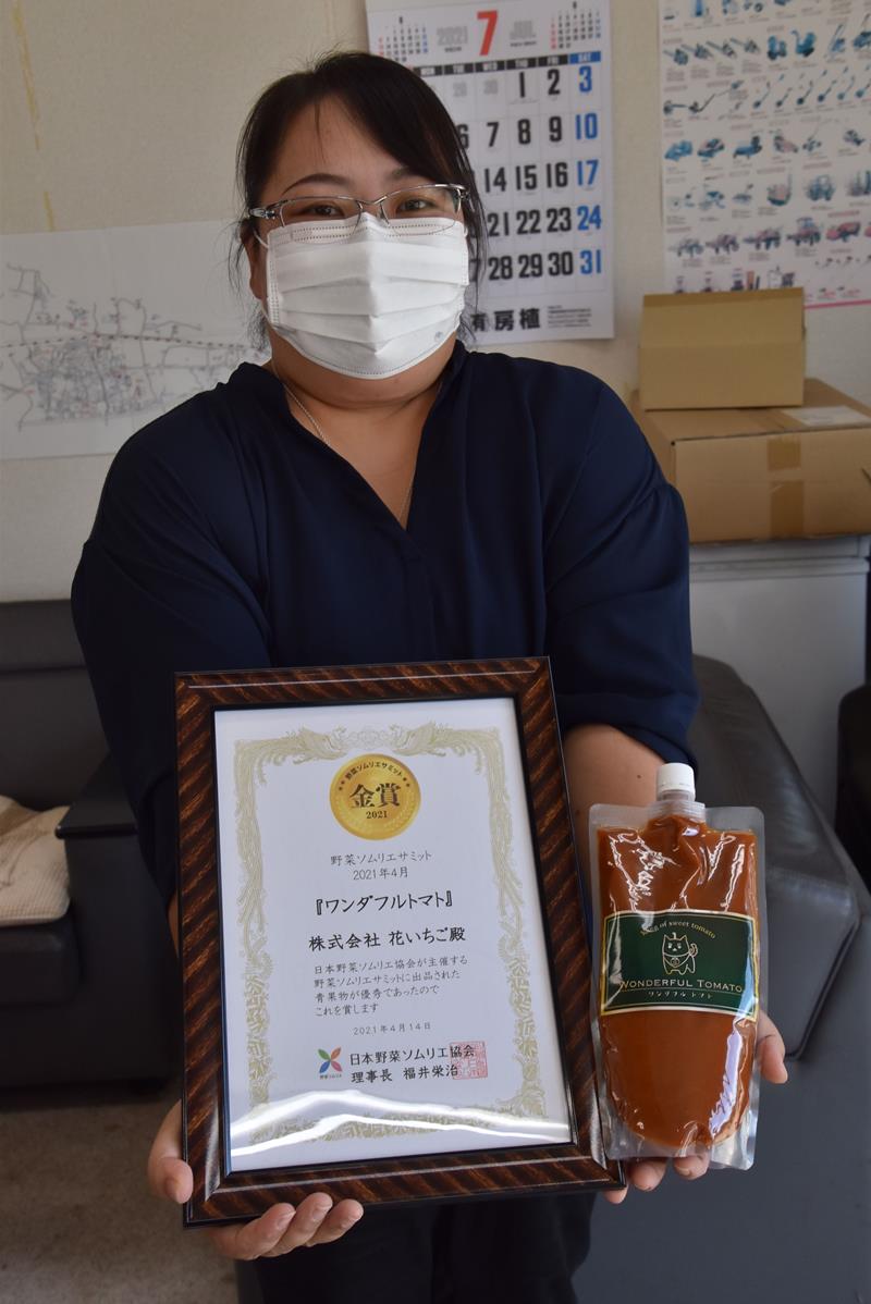 野菜ソムリエサミットの賞状と「ワンダフルトマト」のピューレを掲げる吉野さん=南房総市