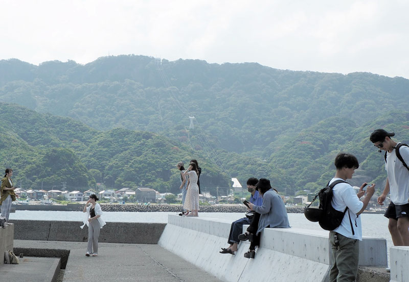 鋸山を望み、写真を撮りながら楽しむ若者たち=31日、富津市
