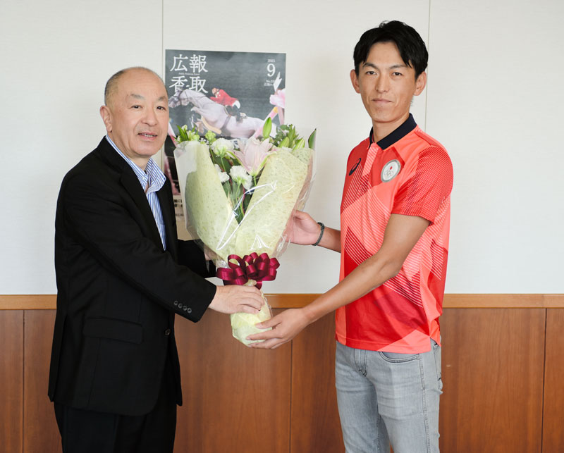 宇井市長（左）から花束を受け取る斎藤選手＝２１日、香取市役所