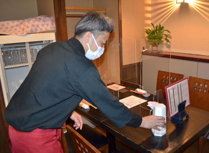 客席に消毒液を設置する根岸さん。重点措置解除で客足の回復に期待を寄せる＝１５日午後３時半ごろ、千葉市中央区