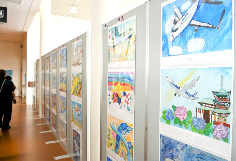 幻想的な世界や地域性ある風景の中に航空機が描かれた絵画作品=芝山町の航空科学博物館