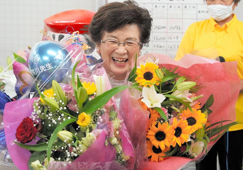 当選祝いの花束を抱えて笑顔を見せる照川氏＝２８日午後１０時半過ぎ、勝浦市