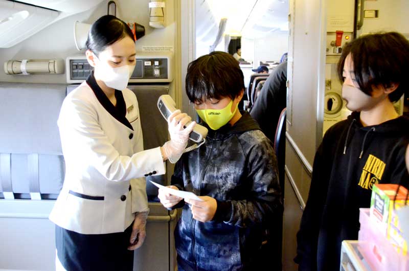 成田空港発着の周遊フライト便で、機内アナウンスを体験する児童=17日