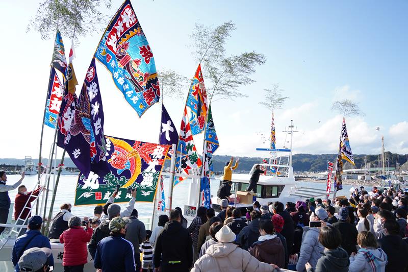 大勢の人が集まった大漁旗はためく新造漁船からの餅まき＝勝浦漁港