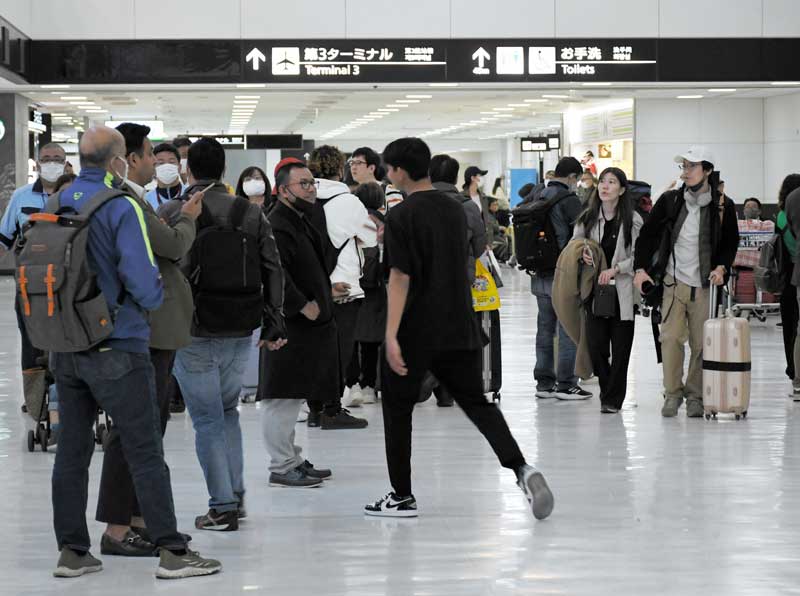 マスクを外した旅客の姿が見られる成田空港の国際線到着ロビー=13日、成田市