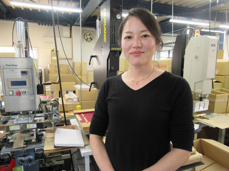 ファイルのシートを貼り付ける機械が並ぶ作業場での永田社長=鎌ケ谷市