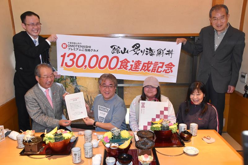 13万食目の客となった竹内さん家族に認定書を手渡す小金会長(左)=館山市