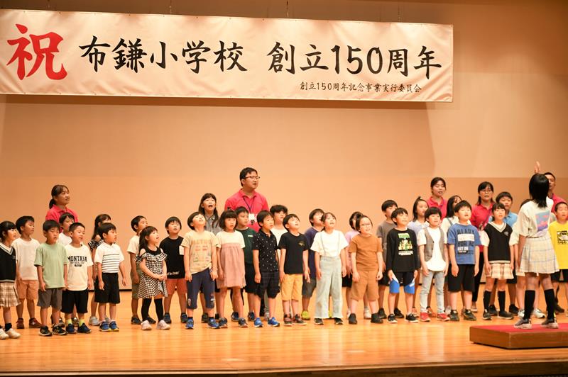 布鎌小の150年の歴史を伝える式典で合唱する児童ら=17日、栄町