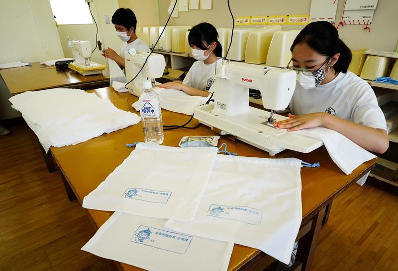 真っ白なさらしから非常用袋を作る勝浦中の家庭科部員＝勝浦市