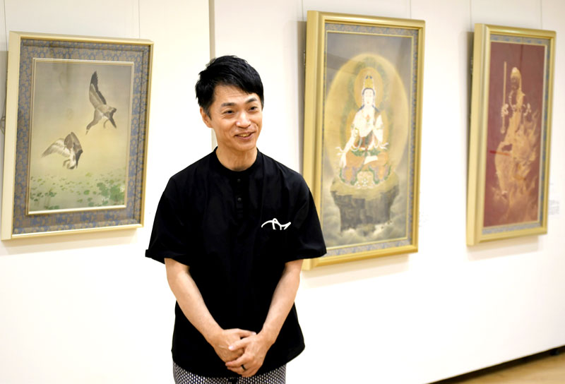 父親の小幡春生氏が描いた絵の魅力を説明する龍生さん=成田市