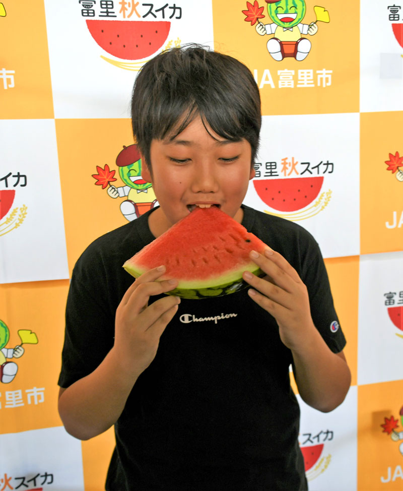 自身が命名した富里秋スイカを頬張る椎名君＝富里市