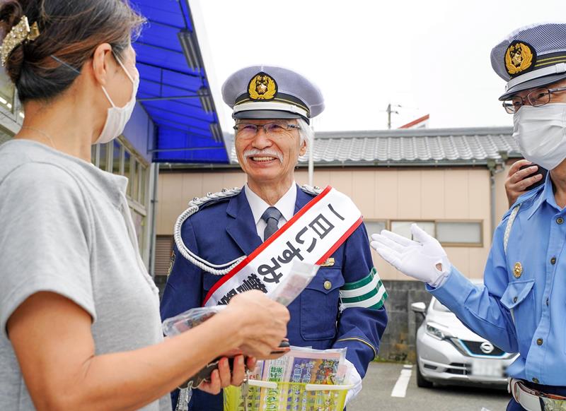 買い物客に交通安全を呼びかける柴崎さん(中央)=21日、御宿町