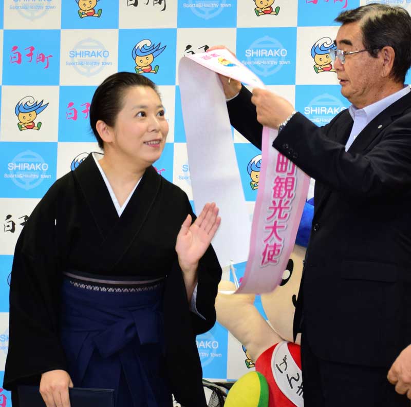 石井和芳町長から観光大使のたすきを掛けられる三遊亭律歌さん(左)=4日、白子町役場