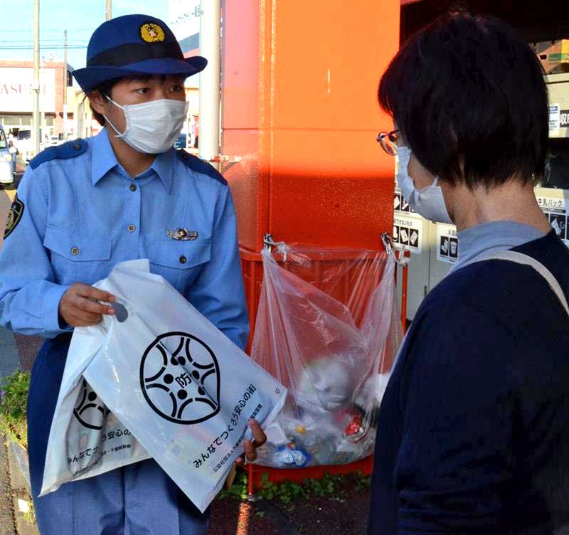 買い物客に自転車の「ツーロック」ができるワイヤー錠が入った袋を配る初任科生(左)=東金市