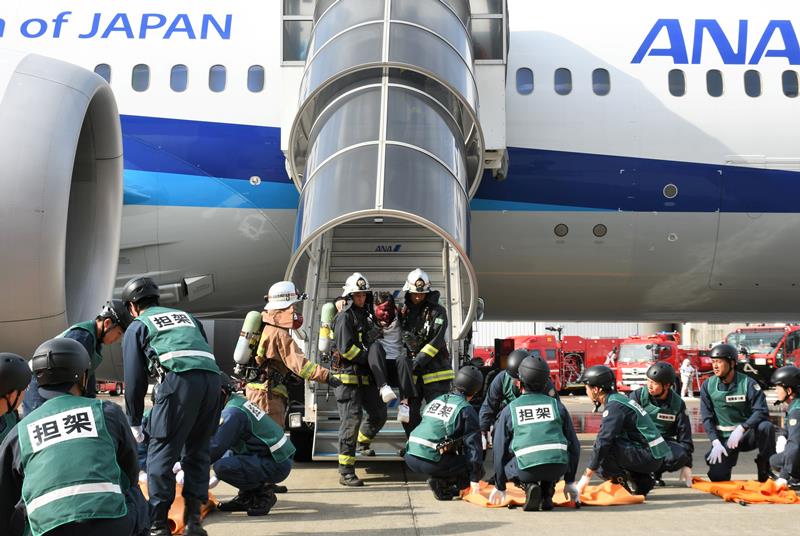 成田空港で炎上したと想定した航空機から旅客を救助する訓練をする消防隊員ら=成田市