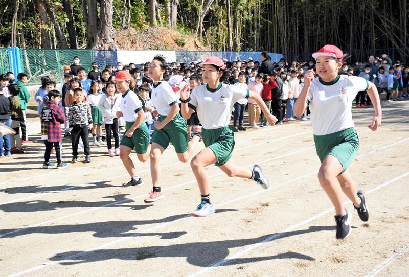 要望が実って広くなった安食小の校庭で、新設された100メートル走路を駆け抜ける児童たち=栄町