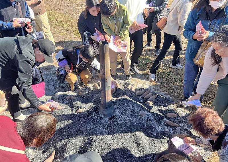 もみ殻でゆっくり焼き上げた焼き芋を手に取る来場者=19日、香取市