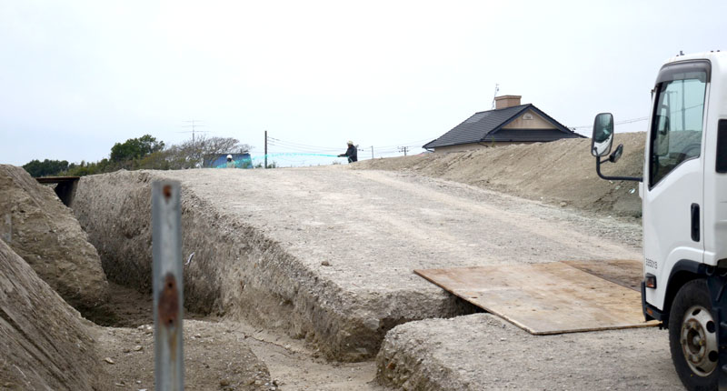 大量の土砂が運び込まれた市有地で飛散防止液を散布する作業員（中央奥）＝５日、山武市小松