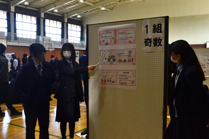 商品企画案をまとめたポスターを使い、発表する実籾高の生徒たち=20日、習志野市