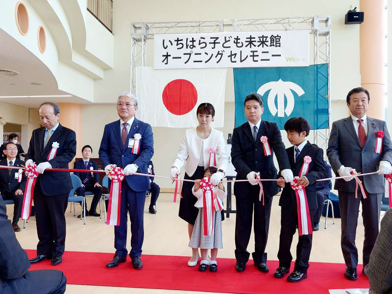 いちはら子ども未来館（愛称＝ｗｅほーる）のオープニングセレモニーで、テープカットに臨む小出市長（手前左から２人目）と愛称考案者の品田さん（中央）ら