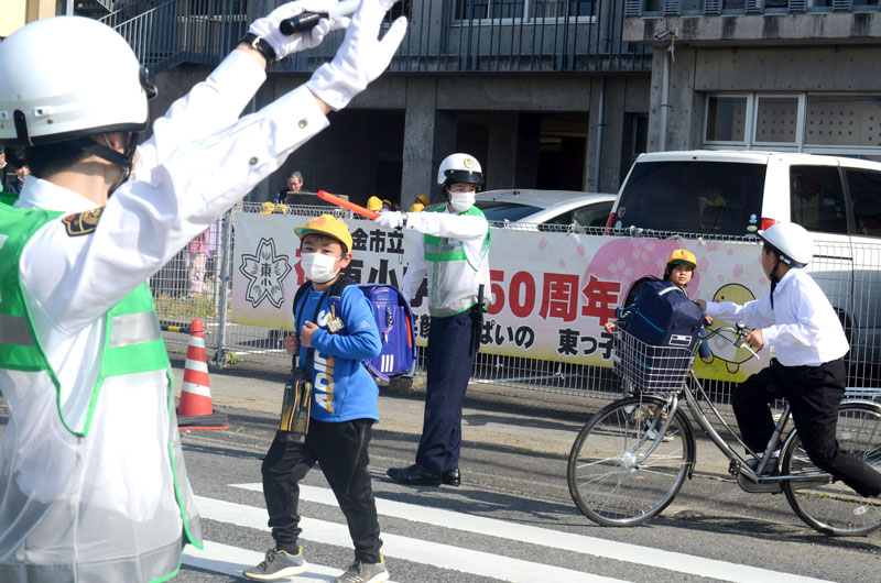 制服姿で誘導棒を手にし、横断歩道を渡る子どもの安全を確保する県警察学校の初任科生＝１５日、東金市