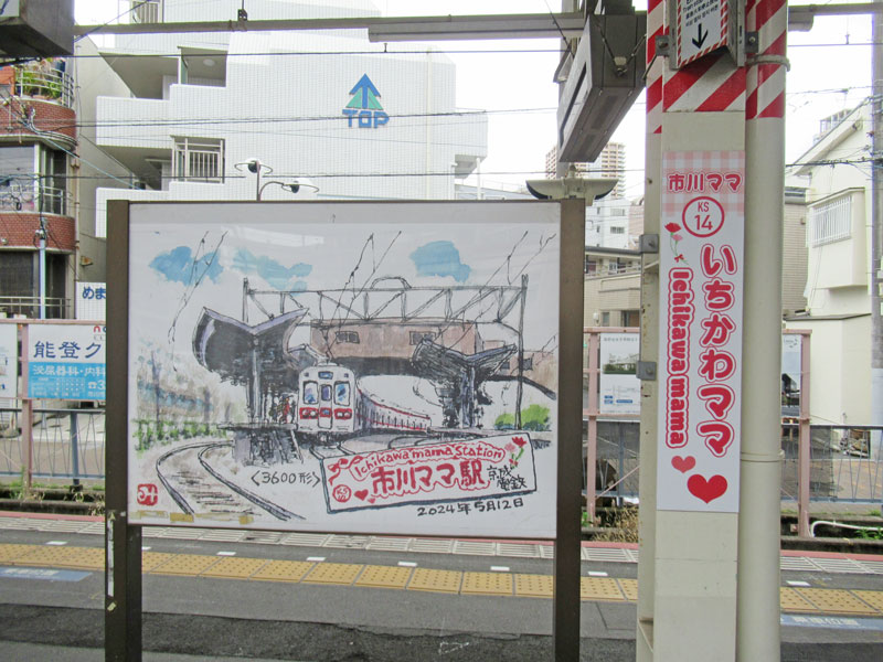 「いちかわママ」のホーム駅名看板。地元在住の画家が描いた同駅イラストも展示＝３０日、市川市