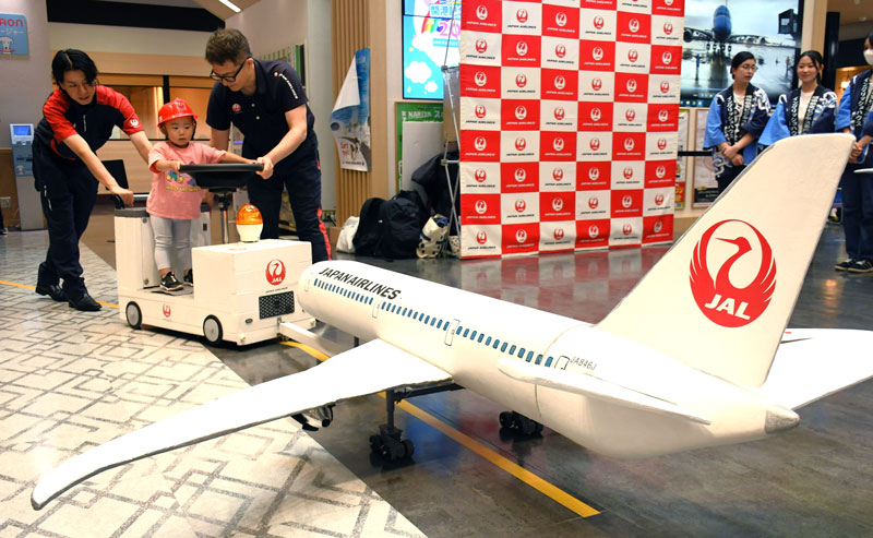 航空機の模型をミニけん引車でプッシュバックする子ども