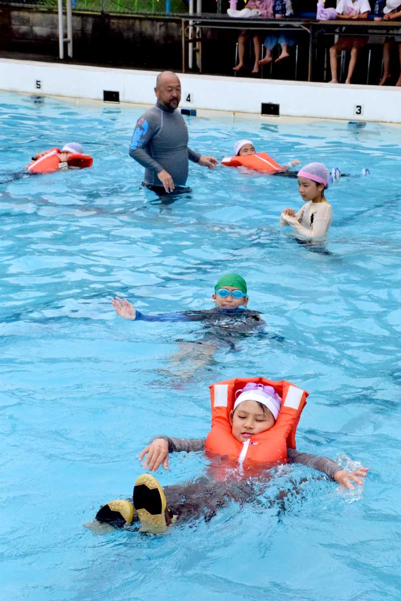 服を着たままプールに入り、有効な泳ぎ方を教わる子どもたち＝１６日、長生村立一松小