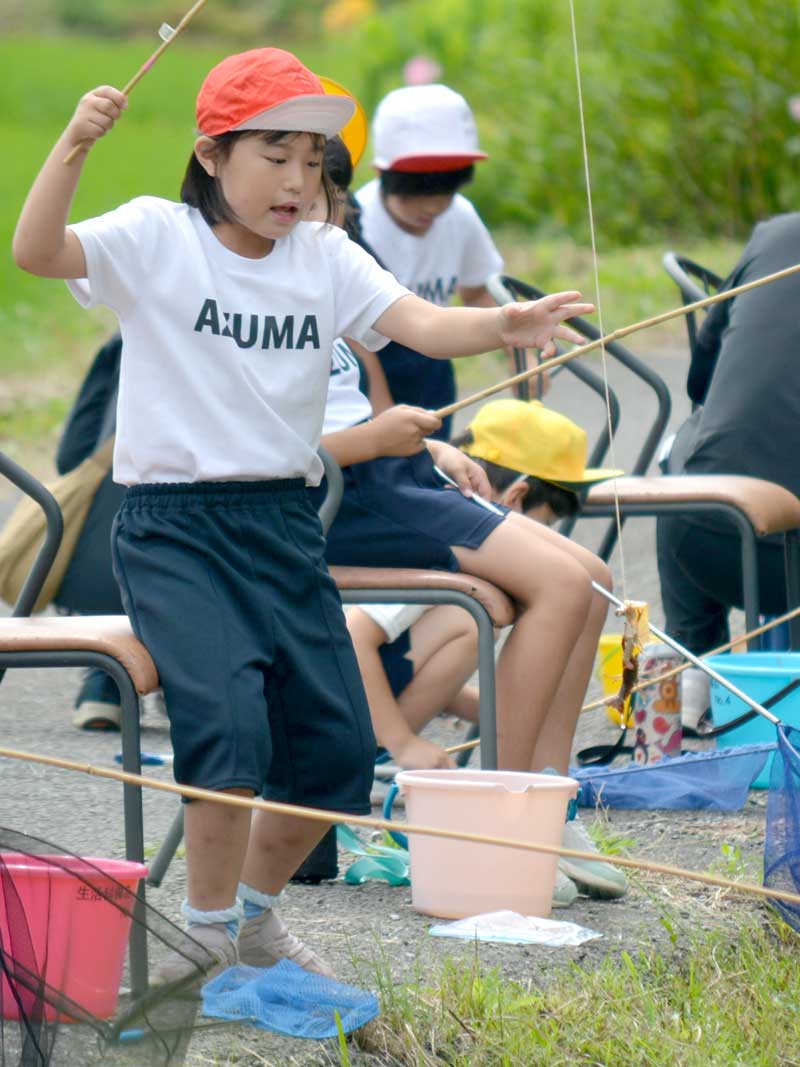 ザリガニを釣り上げ喜ぶ児童
