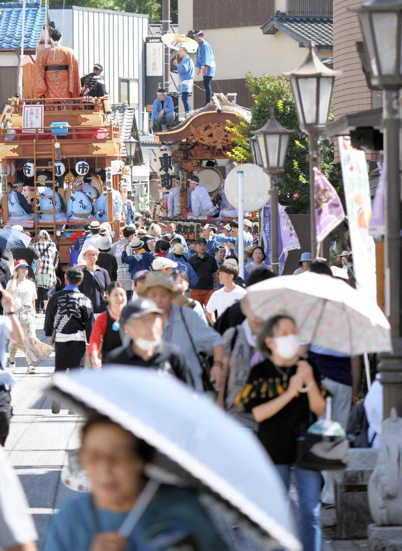 成田伝統芸能まつりが開かれた成田山新勝寺の参道で、日傘を差したり帽子をかぶったりして歩く人々=14日午後、成田市