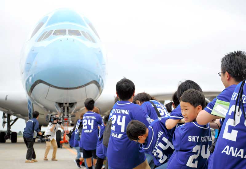 成田空港で超大型機のフライングホヌを引っ張る親子たち＝６日、成田市