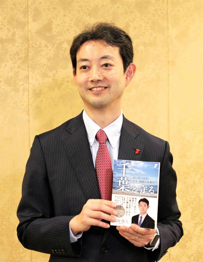 出版記念パーティー後、自著を手に写真撮影に応じる熊谷知事＝１４日、千葉市中央区