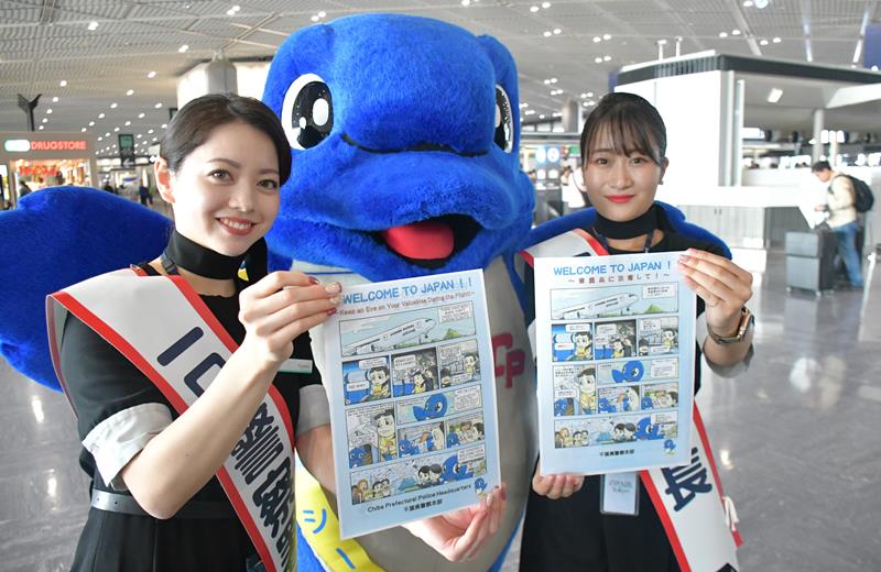 航空機内での窃盗被害防止に向けた注意喚起の漫画を紹介する一日警察署長の客室乗務員ら=22日、成田市の成田空港
