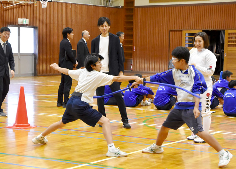 スマートフェンシングを体験する第一中生徒と宇山さん（中央奥）＝館山市