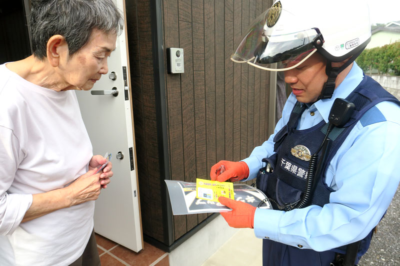 １人暮らしの高齢女性宅を訪問し、防犯対策ステッカーを手渡す橋本さん＝１０月、富津市