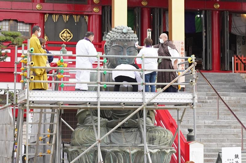 大仏の顔などを丁寧に拭く平幡住職(右)や参加者=13日、銚子市