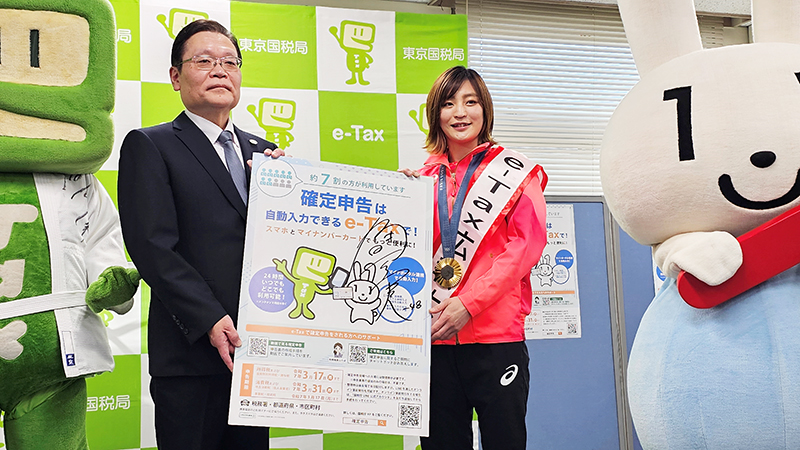 ポスターを手に「ｅ－Ｔａｘ」をＰＲする角田選手（右）＝３０日、千葉市花見川区の千葉西税務署