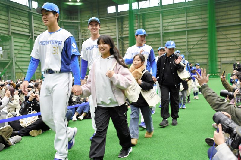 地元の子どもたちと手をつないで入場する選手ら＝１９日、鎌ケ谷市のファイターズ鎌ケ谷スタジアム