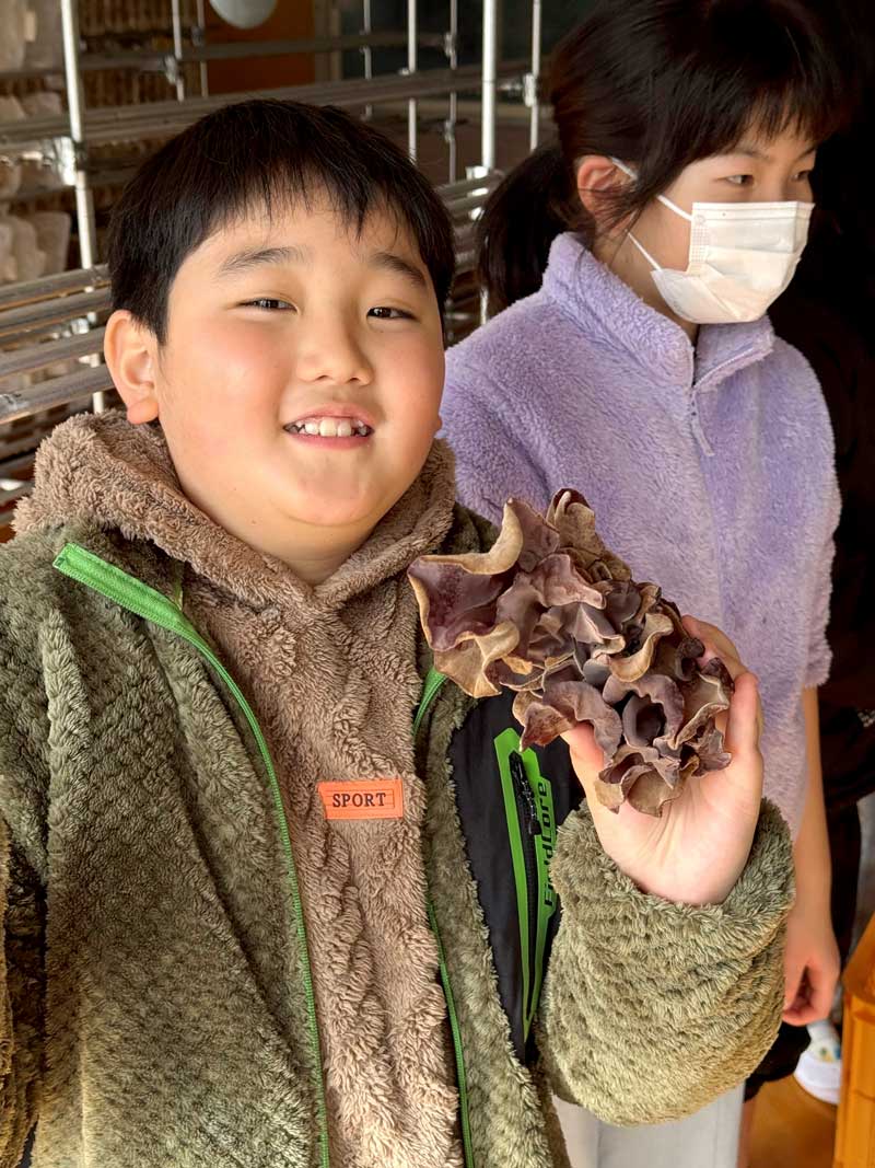 たくさんのキクラゲを収穫し、満足そうな表情を浮かべる房南小児童＝６日、館山市