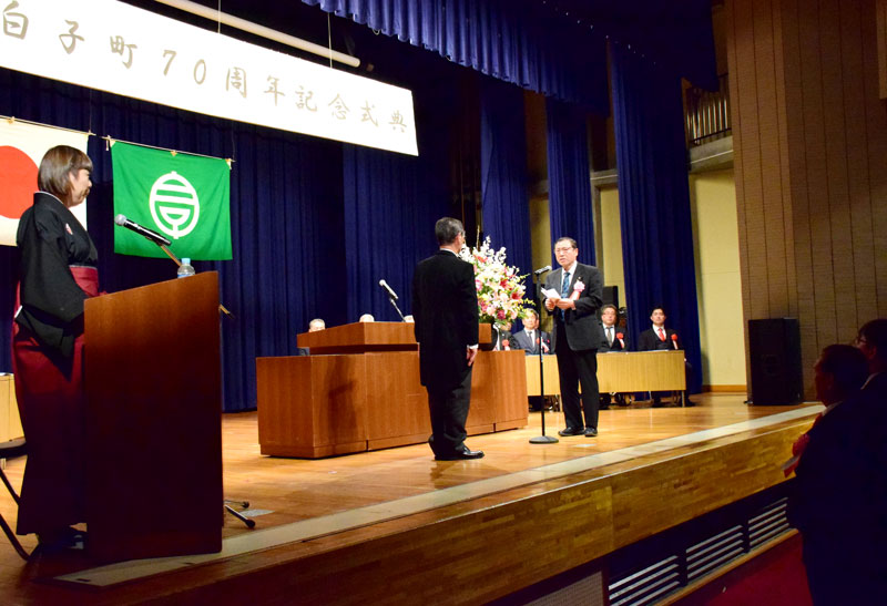 石井町長（中央左）に謝辞を述べる表彰受賞者。司会は落語家の三遊亭律歌さんが務めた＝１１日、白子町