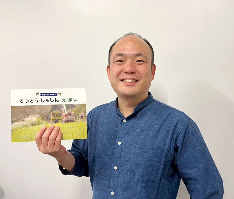 初めて刊行した「おとうさんとぼくのてつどうしゃしんえほん」を手に取る高橋寿太郎さん＝２０２４年１２月、横浜市