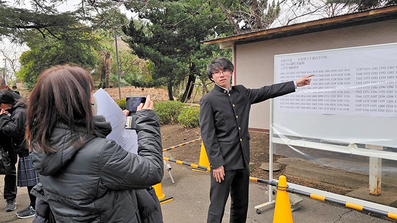 自身の受験番号を指さし、合格を喜ぶ受験生=4日午前、千葉市中央区の県立千葉高校