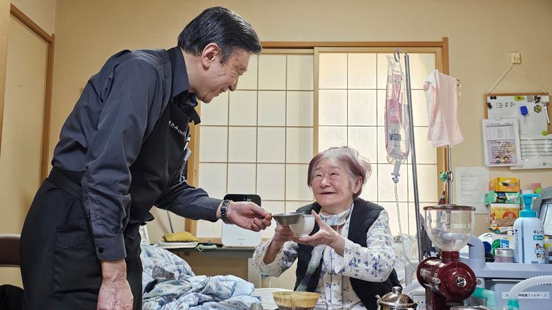 北見さん(左)にコーヒーをいれてもらい、笑顔で乾杯する下平さん=2月27日午後、佐倉市