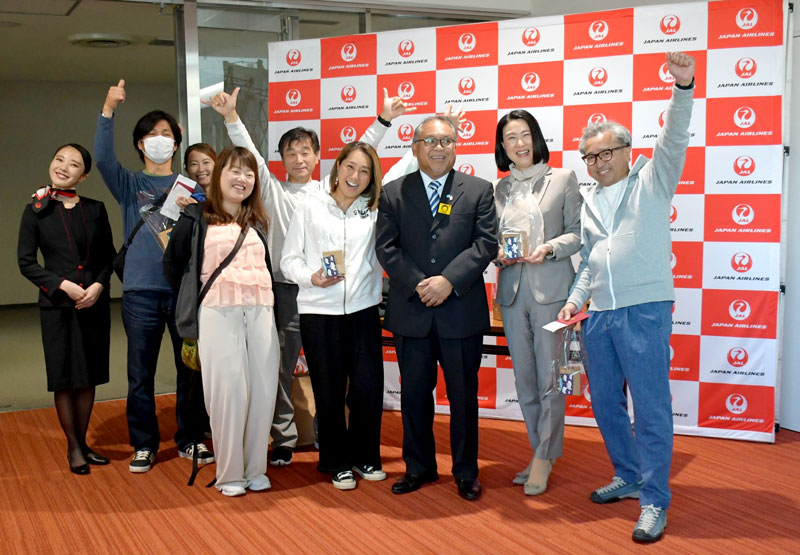 駐日パラオ特命全権大使のピーター氏（右から３人目）を囲むチャーター便の搭乗客ら＝成田市の成田空港
