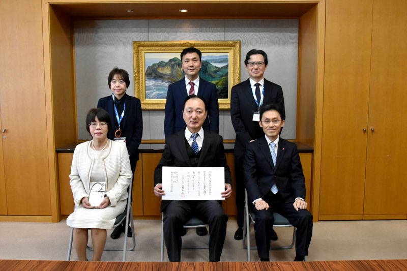 伝達書を持つ杉田理事長（前列中央）＝県庁