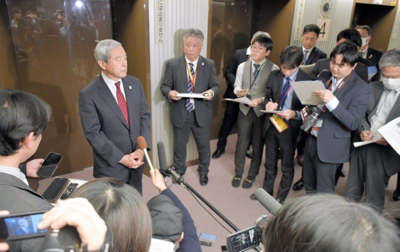 報道陣に囲まれる中で成田空港の滑走路新設など機能強化工事の本格着工について説明するNAAの田村社長(左奥)ら=4日、東京都千代田区の国土交通省