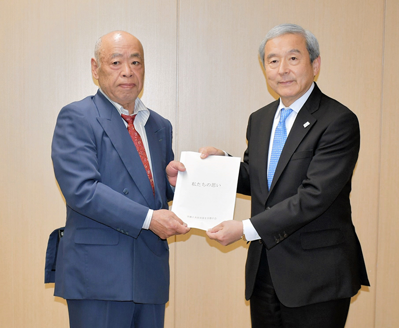 ＮＡＡの田村社長（右）に「私たちの思い」を手渡す石井会長＝成田市